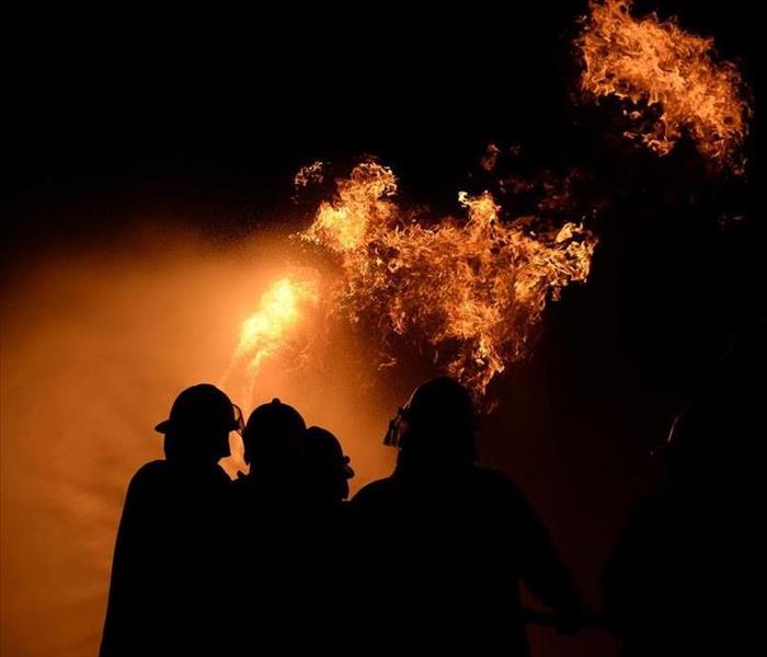 Firemen silhouetted against raging house fire