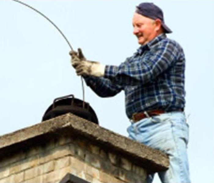 Man on a ladder cleaning chimney