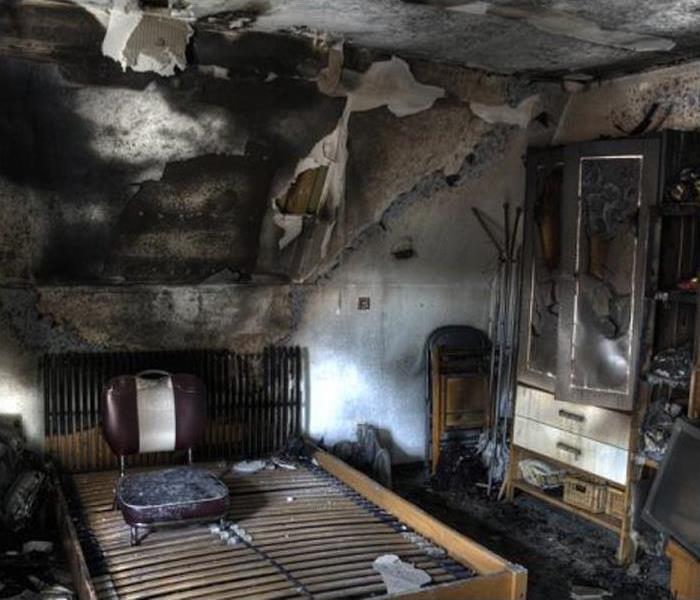 bedroom with significant fire damage to wall and ceiling