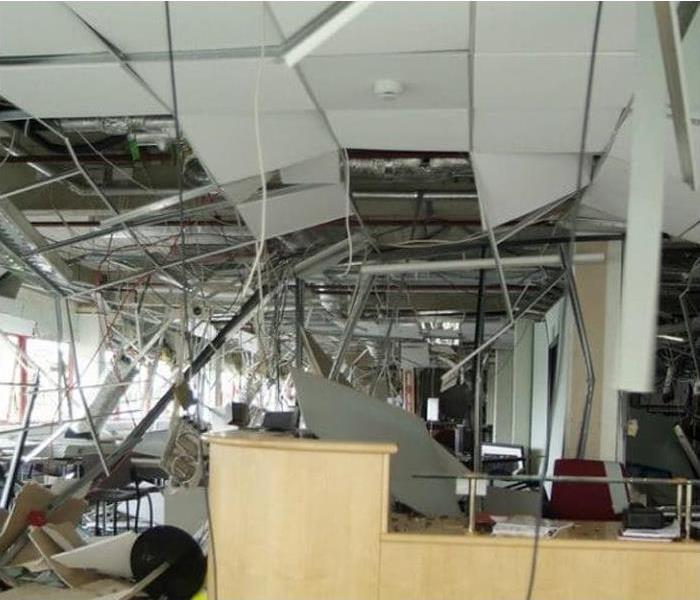 Damaged office space with collapsed ceiling, exposed wiring and broken windows